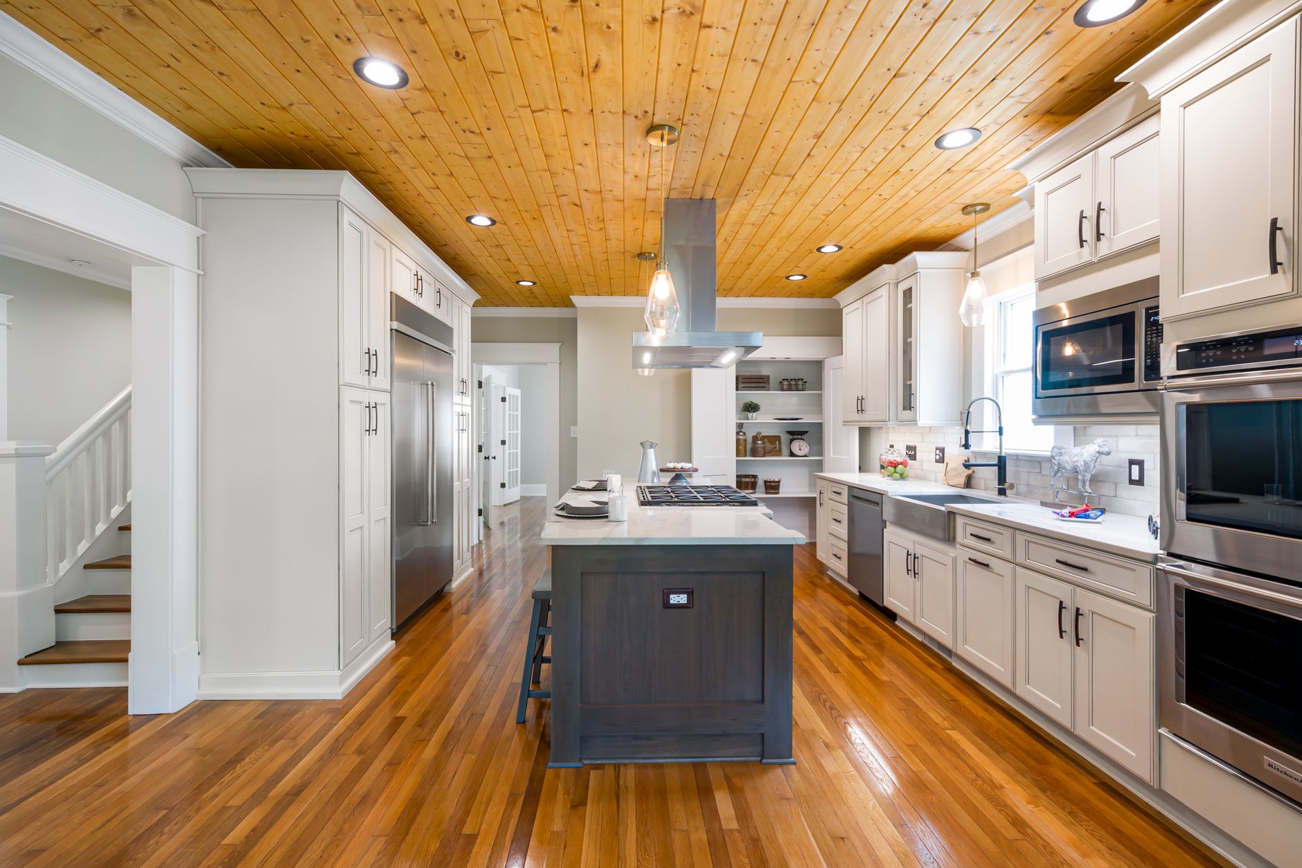 Spacious modern kitchen featuring a wooden ceiling, island countertop, and stainless steel appliances in Scottsdale, AZ